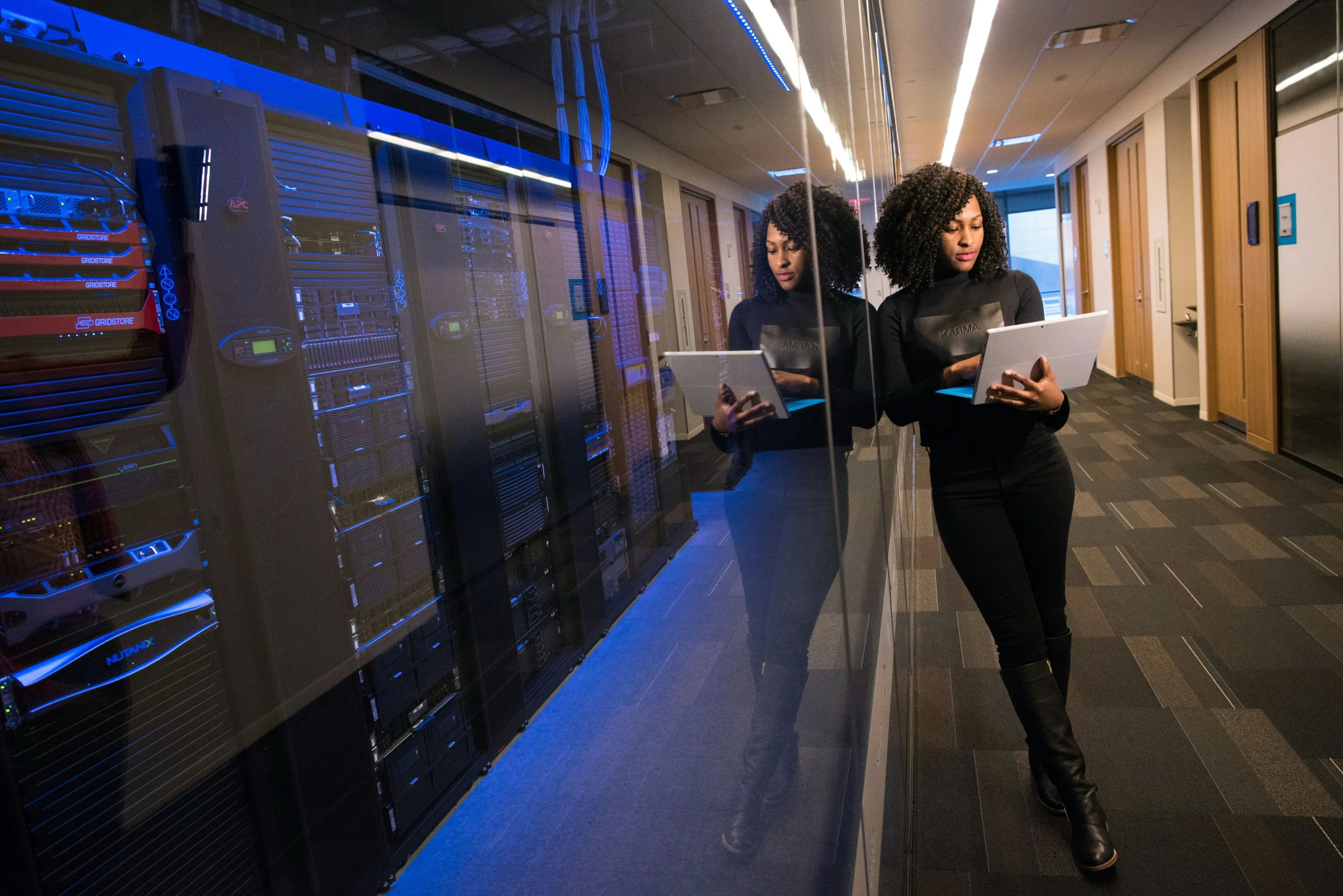 A Discern team member reviews analytics on a laptop beside a secure server room — illustrating data handled under enterprise-grade physical and network security.